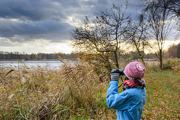 Lady with binoculars bird watching by a lake. Birdwatching Ireland