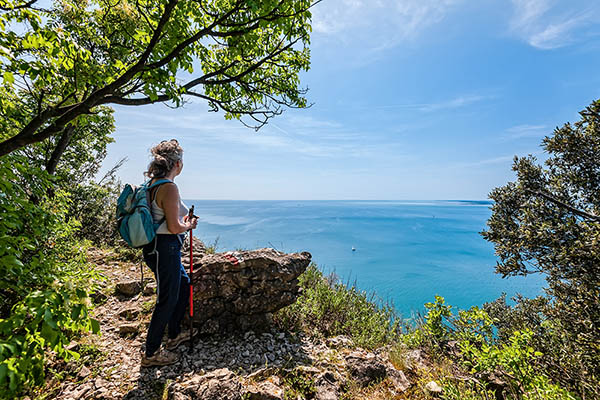 Mature hiker female with backpack looking forward on sea, sky