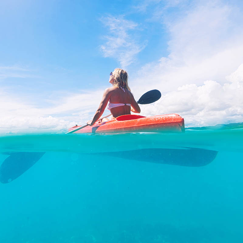 Woman paddling a kayak in a tropical bay