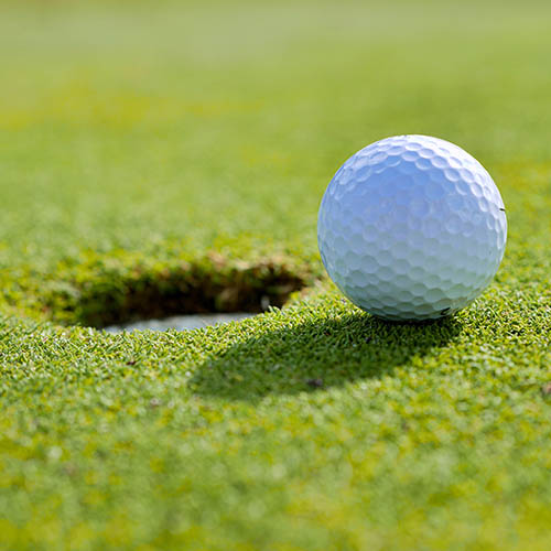 Close up of a golf ball on grass by the hole