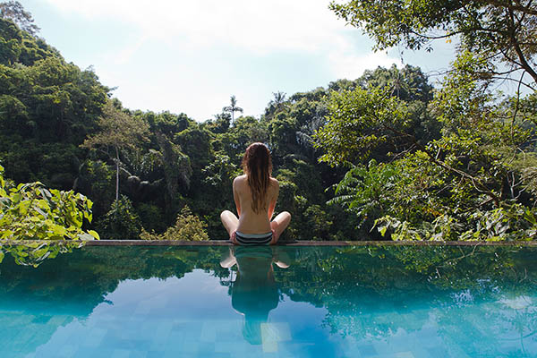 Young woman sitting on the edge of a tropical jungle pool