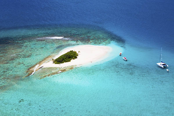 aerial shot of a deserted island in British Virgin Islands with boats anchored by