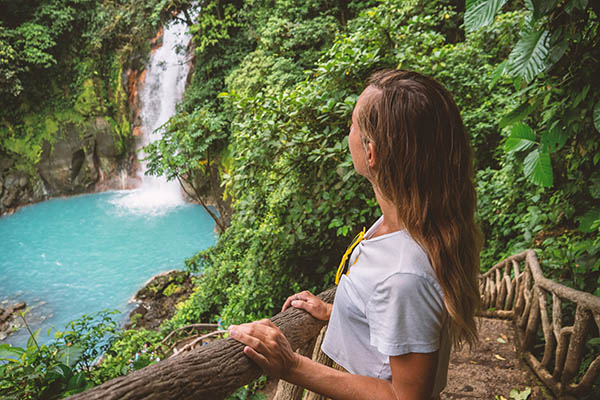 Young woman looking at a turquoise waterfall in Costa Rica