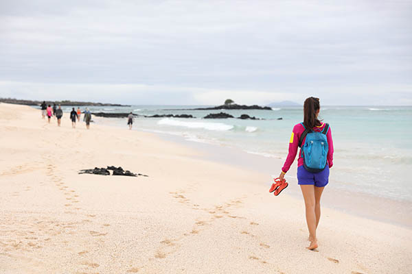 Woman walking barefoot on Playa las Bachas Beach on Santa Cruz Island, Galapagos Islands