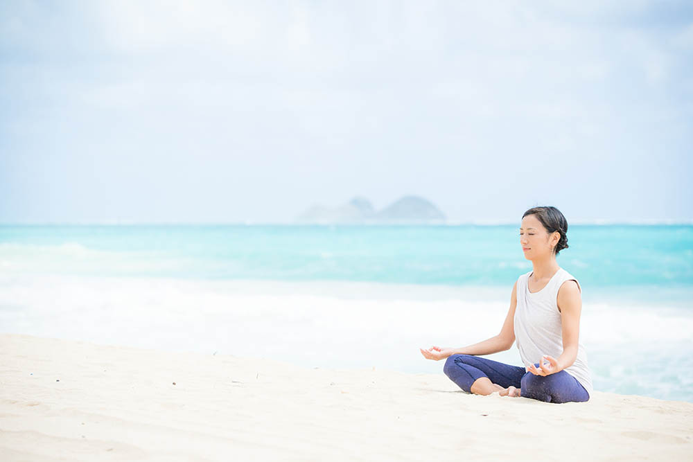 Japanese woman on a beach doing yoga