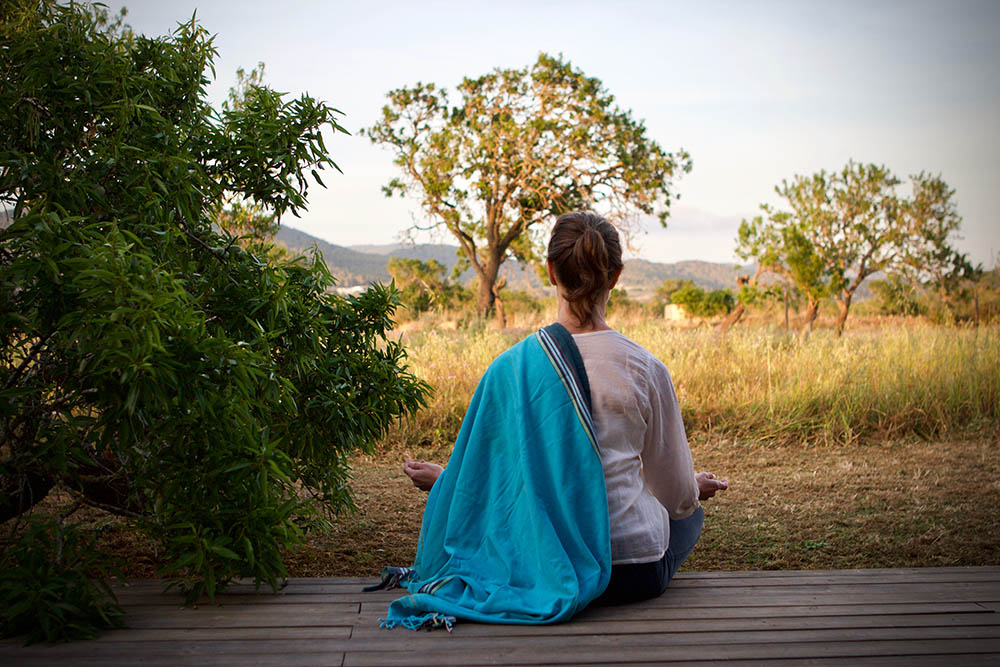 Woman in lotus position meditating on a wooden deck in Botswana