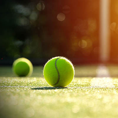 Tennis balls on grass court with sunlight