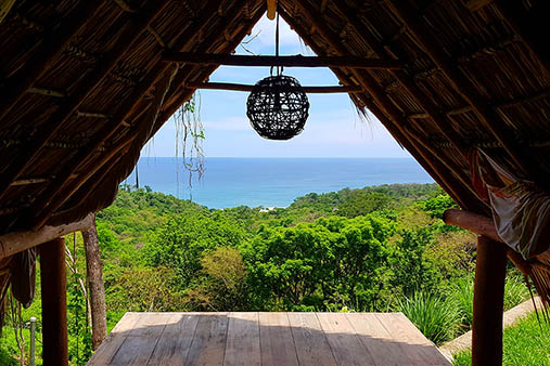 Yoga and massage hut with a stunning view over the lush mountain and trees down to the beach in Nicaragua