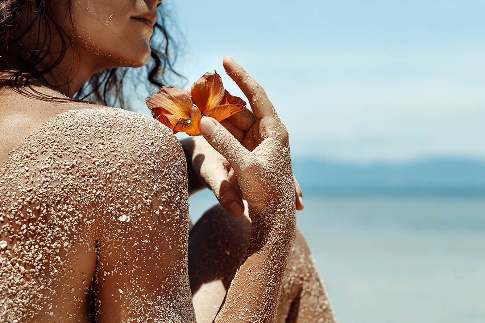 Close up of a woman’s hands holding flower on a tropical beach