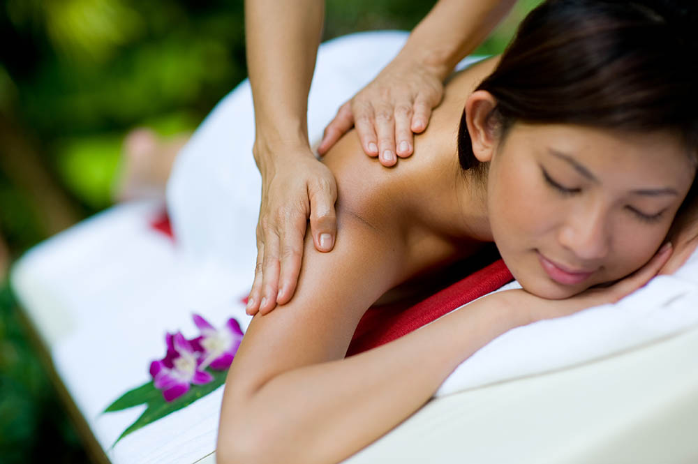 Young Asian woman receiving a massage in a tropical setting