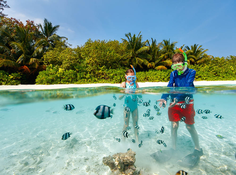 underwater photo of kids having fun in ocean enjoying snorkeling with tropical fish