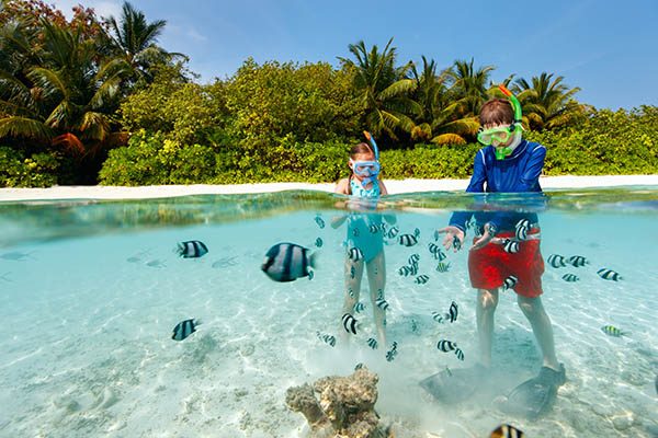 underwater photo of kids having fun in ocean enjoying snorkeling with tropical fish