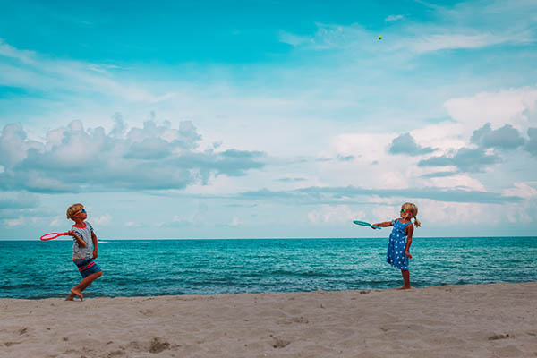 boy and girl play tennis on beach