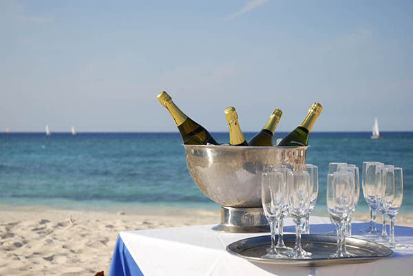 Ice bucket with champagne & glasses laid out next to the ocean