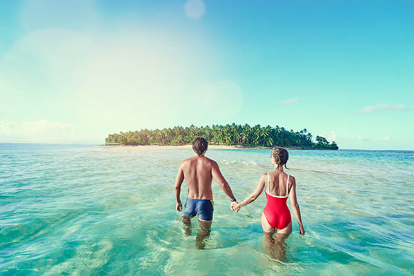 Honey moon on the sea shore. Back view of loving couple bathing together on beautiful tropical island beach.