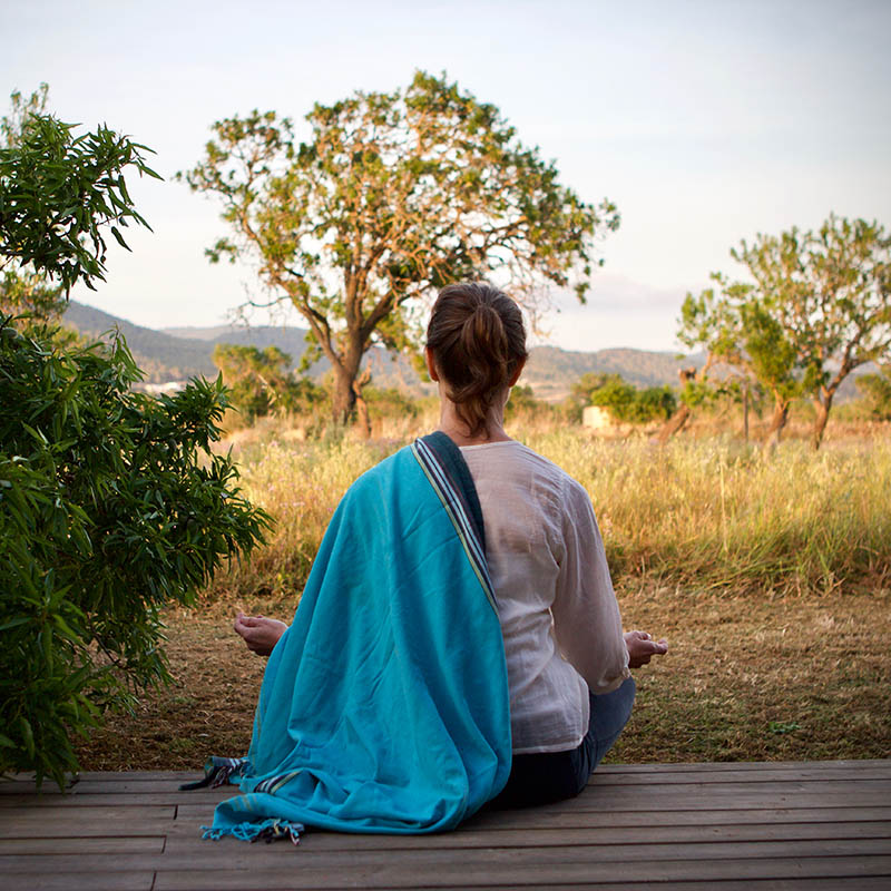 Woman in lotus position meditating on a wooden deck in Botswana