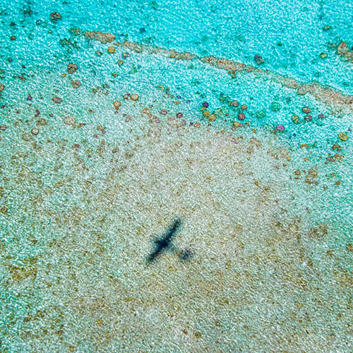 Small aircraft flying over turquoise lagoons