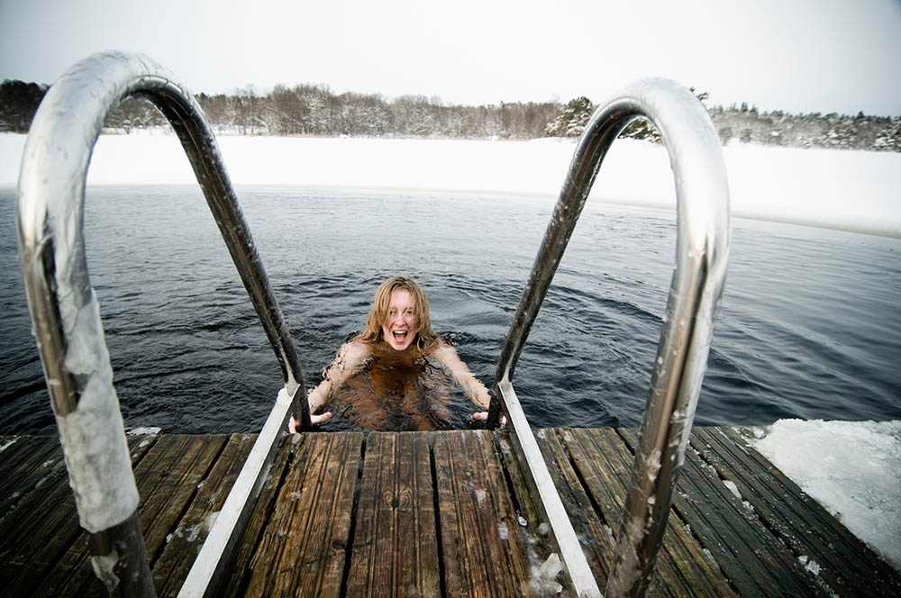 Girl climbing out of ice cold water in Sweden