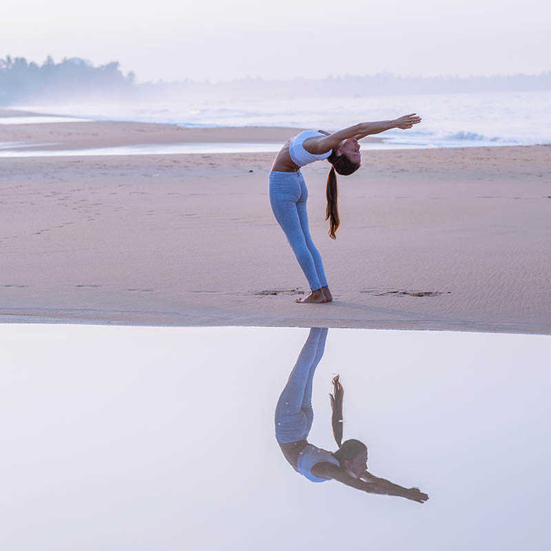 Woman practicing yoga on the beach