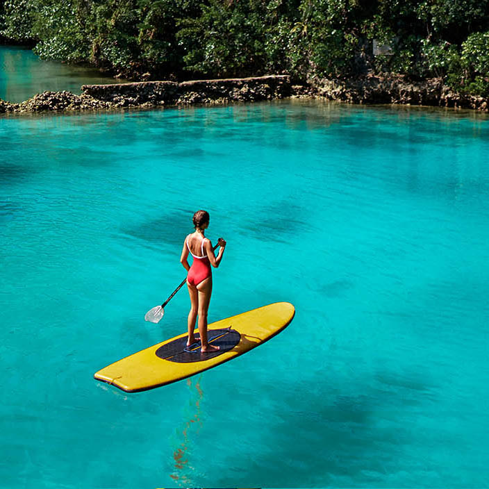 Young woman on SUP in calm lagoon in the Philippines