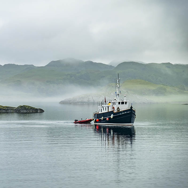 Boat driving through in the foggy sea in the Highlands of Scotland