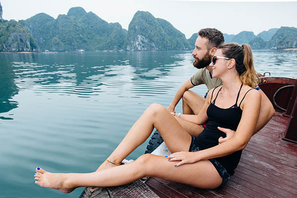 Couple hugging each other on the deck of cruise ship with view on Ha long Bay and calm sea.