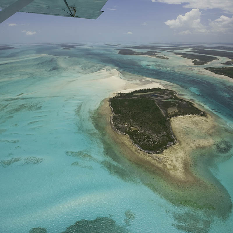 Small aircraft flying over islands in the Bahamas