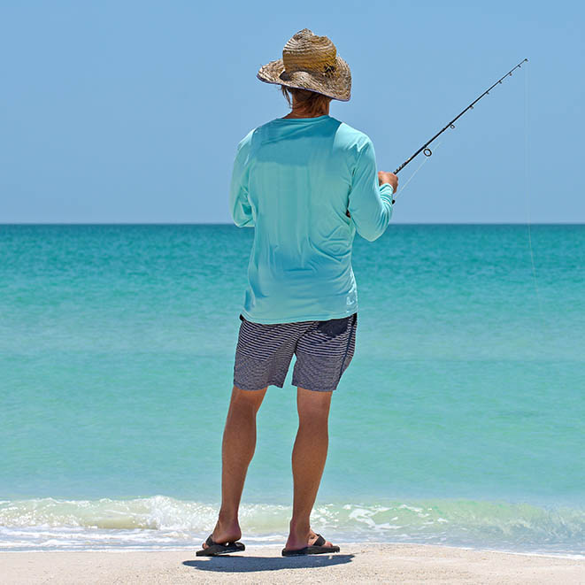 man on the beach fishing in shallow waters