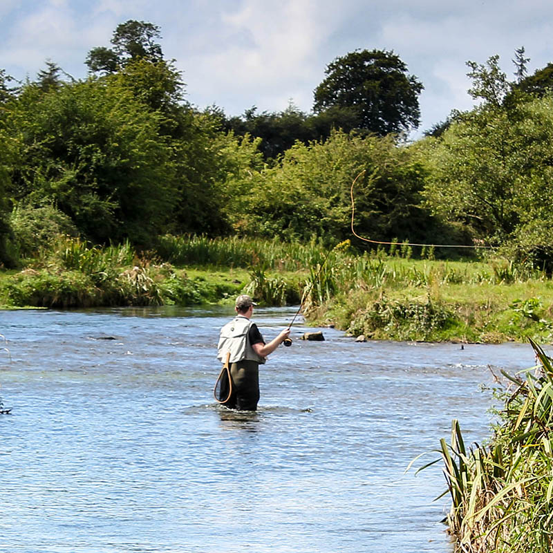 Man fly fishing casts on Irish river