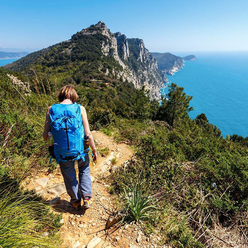 Woman with backpack hiking towards Portovenere in Cinque Terre, Italy