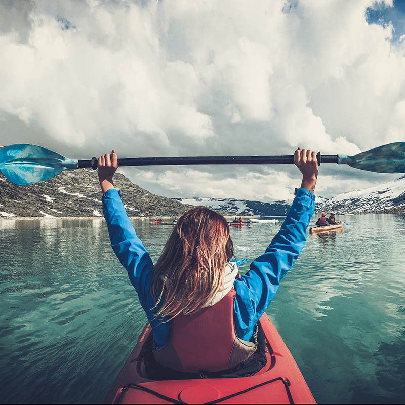 Woman kayaking on Styggvatnet glacier lake near Jostedalsbreen glacier. Norway