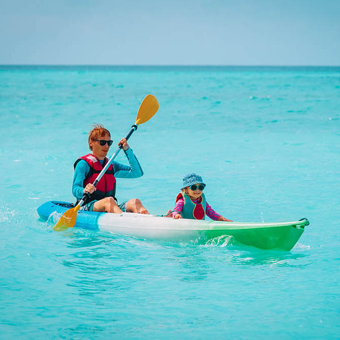 father and little daughter kayaking on beach