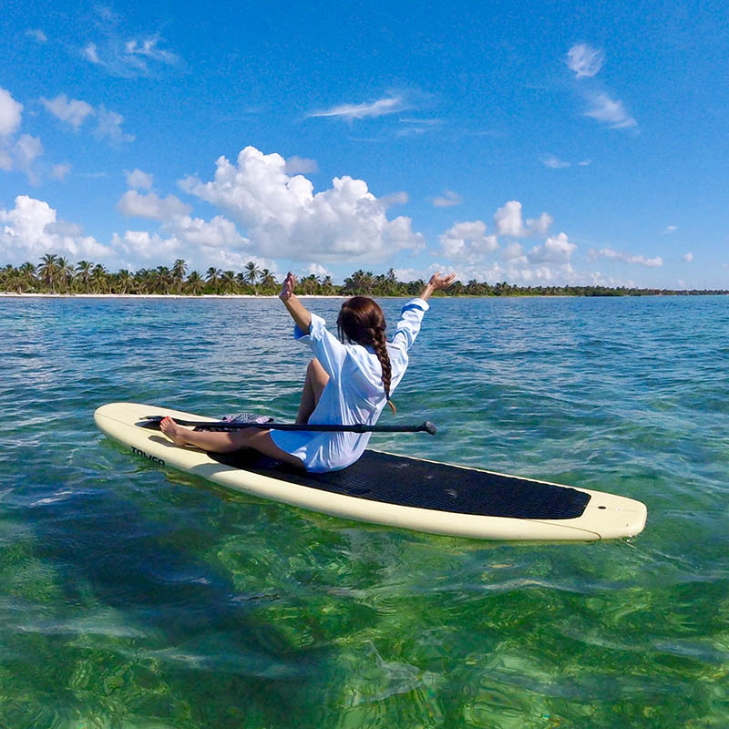 A surfer walks along a jetty towards luxury over-water villas at an exclusive resort in the Maldives