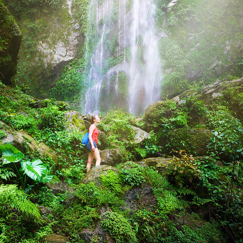 Woman looking at waterfall in Central America jungle. Honduras