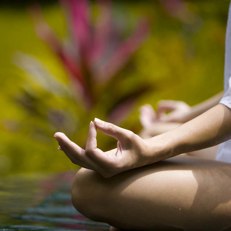 Woman sitting in tropical setting in yoga pose