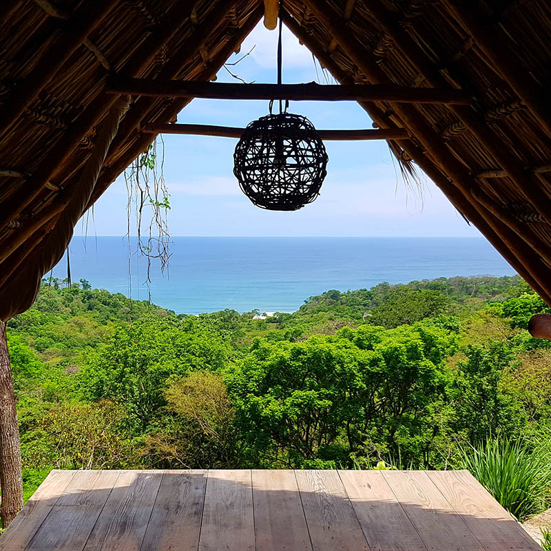 Yoga and massage hut with a stunning view over the lush mountain and trees down to the beach in Nicaragua