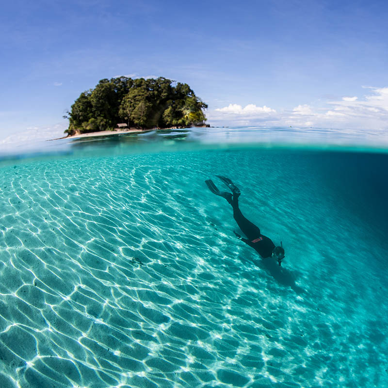 A snorkeler does some free diving along a sandy slope in the Solomon Islands