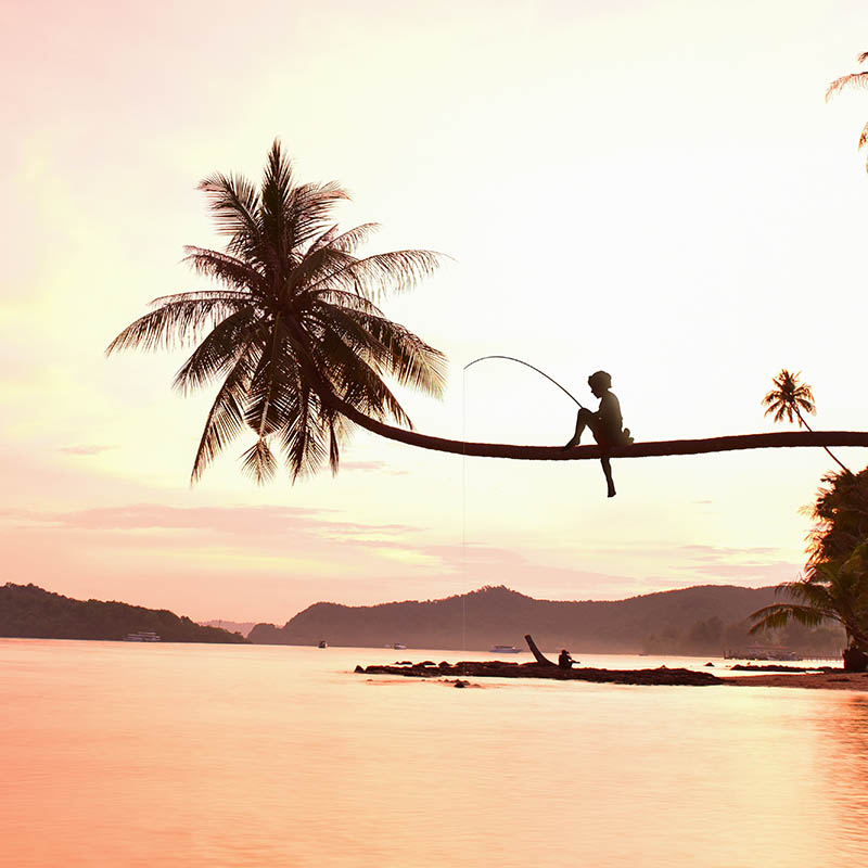 Young boy fishing on a tropical island at sunset