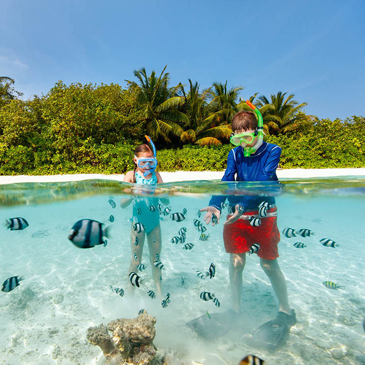 underwater photo of kids having fun in ocean enjoying snorkeling with tropical fish