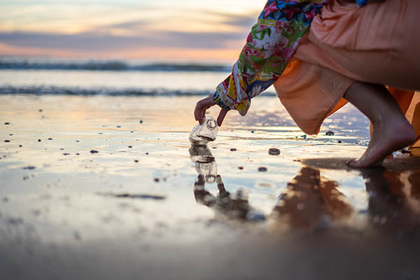 Woman picking litter up from a beach