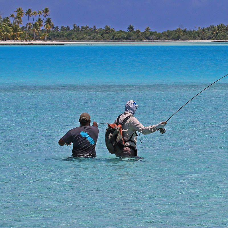 Man flyfishing with a guide in turquoise ocean in French Polynesia