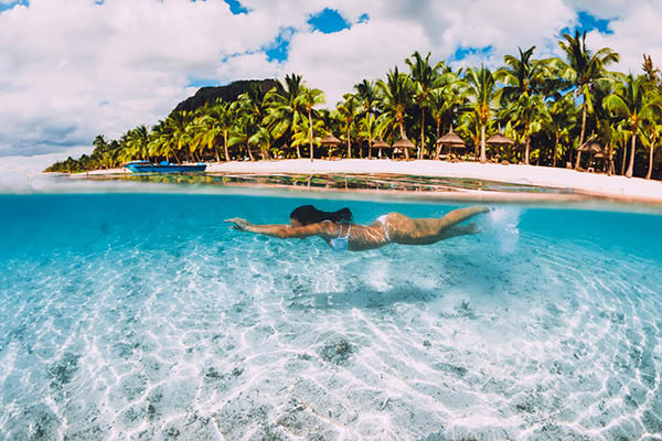 Young attractive woman swimming underwater in transparent blue ocean at Mauritius