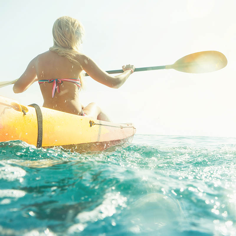 Woman exploring calm tropical bay by kayak