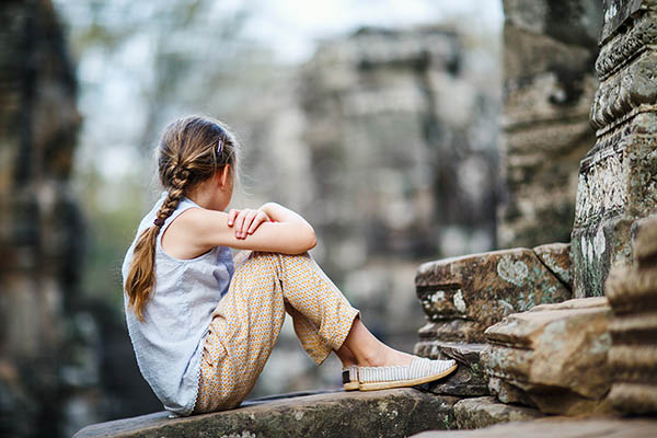 Child sitting in Preah Khan temple, Angkor, Cambodia