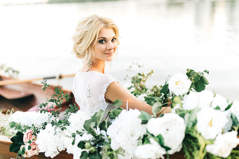 Beautiful bride on a small boat surrounded by flowers