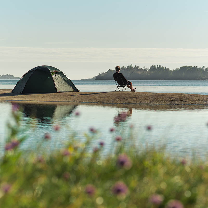 Man sitting on a chair on an island with flowers in the foreground