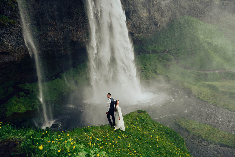 view of happy couple near beautiful grand waterfall in Iceland