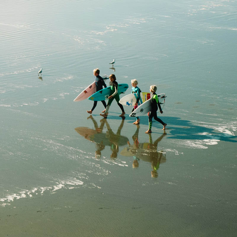 Surfers walking along the ebach at New Brighton, Christchurch, New Zealand