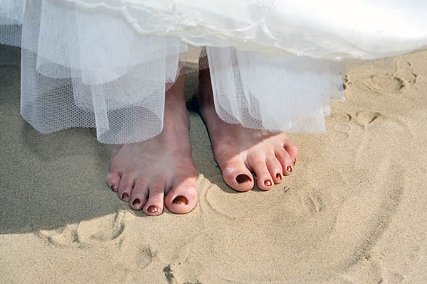 Close-up of a bride's bare feet on a sandy beach