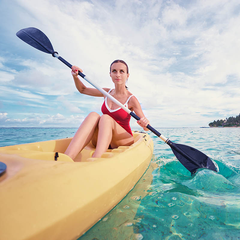 Young woman paddling a  kayak in a tropical bay